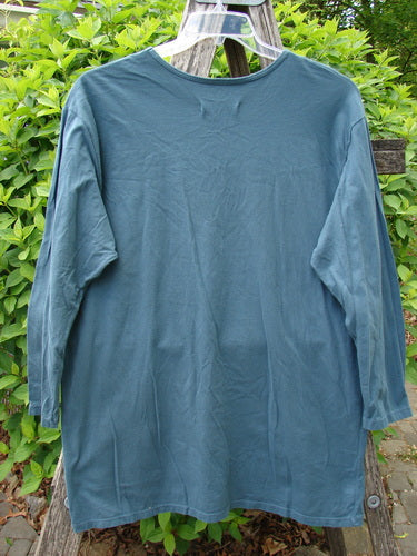 Barclay Long Sleeved Studio Tee Flower Garden Block Tealen Size 0, displayed outdoors on a transparent hanger, features a boxy shape, long sleeves, and a unique flower garden block pattern.