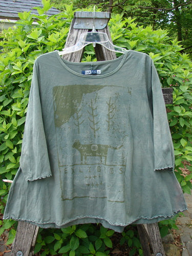 Barclay Crop A Lined Cafe Tee Cow Farm Grass Size 0, featuring a subtle cat silhouette graphic, hangs on a ladder outdoors, showcasing its A-line shape and rolled neckline with sweet curly edgings.