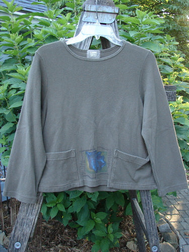 1999 Thermal Boatneck Pullover Fall Leaf Mud Size 0, displayed on a hanger, features long sleeves, front billowy pockets, and a crop boxy A-line shape, crafted from stretchy cotton thermal fabric.