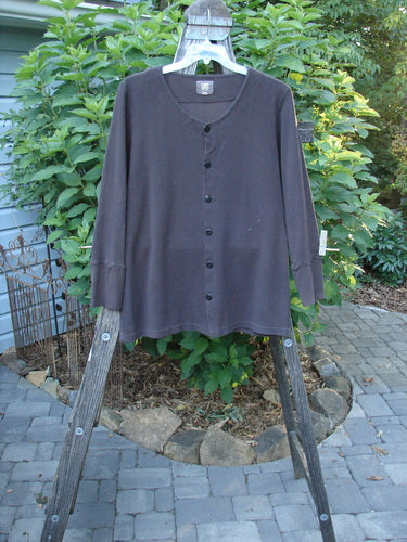 Long-sleeved 2000 Thermal Lu Top Unpainted Brum Size 1 displayed on a wooden rack, featuring ribbed cuffs, rubberized buttons, and a slight A-line shape.