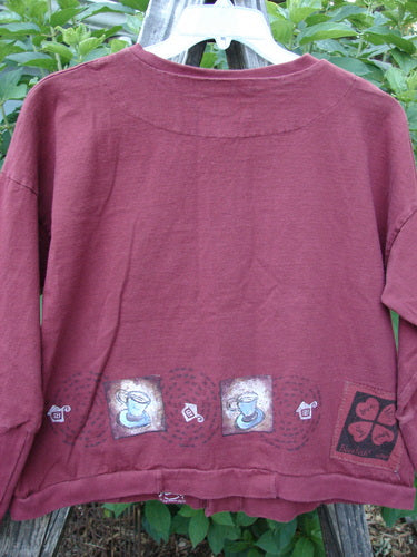 1999 Cottage Cardigan Heart Cup Cinnamon Size 0, featuring a teacup and teacups design on a red background, with ribbed lower sleeves, double-layered elements, and oversized vintage buttons.