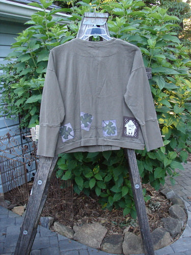 1999 Cottage Cardigan Forest Leaf Mud Size 0 displayed on a hanger, showcasing its long sleeves, ribbed lower sleeves, double-layered front pocket, and oversized buttons, with the Blue Fish Patch and forest leaf design.