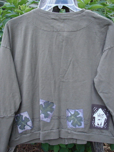 Close-up of the 1999 Cottage Cardigan Forest Leaf Mud Size 0, showcasing its ribbed lower sleeves, double-paneled back shoulder, and three oversized vintage buttons, emphasizing its unique, textured design.