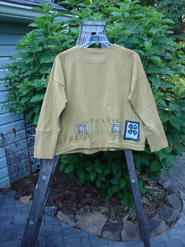 1999 Cottage Cardigan Campfire Gold Size 1 displayed on a rack, featuring ribbed lower sleeves, double-layered neckline, hemline, front pocket, drop shoulder seams, and oversized vintage buttons.