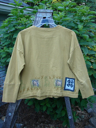 1999 Cottage Cardigan Campfire Gold Size 1 on a hanger, featuring long sleeves, ribbed lower sleeves, a square boxy shape, front pocket, oversized buttons, and Blue Fish patch with campfire theme paint.