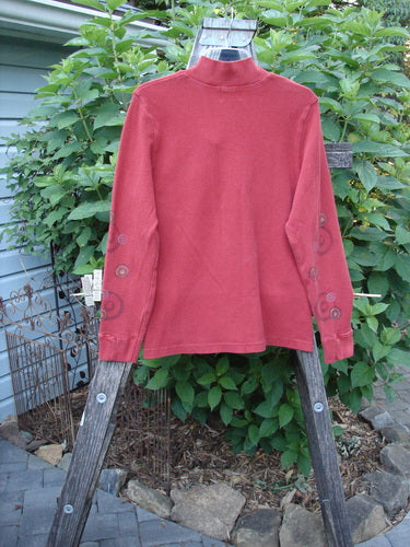 2000 Thermal Boann Top Bubble Bittersweet Size 1 displayed on a clothes rack, showcasing its thick ribbed V neckline, partially ribbed cuffs, and tapered waist.