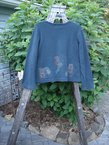 1999 Thermal Boatneck Pullover Heart Peacock Size 1 displayed on a wooden rack, showcasing its A-line shape, billowy pockets, and heart-themed design in a garden setting.