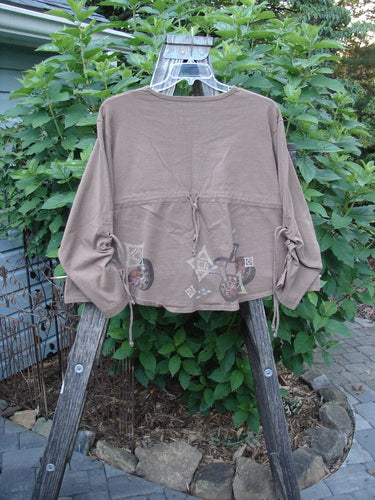 Brown shirt with diamond pattern and sleeve lacings on a hanger; titled 1997 Chandra Top Holiday Diamond Mandorla Size 1.