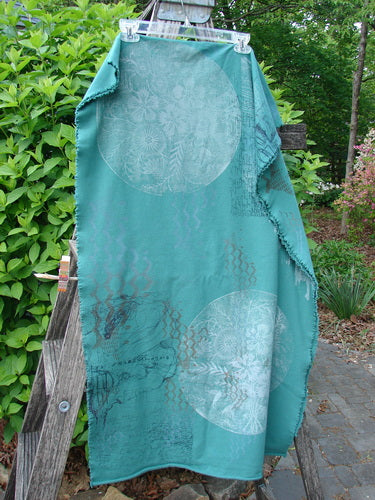 Barclay Heavy Weight Organic Sweatshirt Art Wrap Moon Garden Emerald OSFA draped over a ladder, displaying circular floral motifs and curly edgings, in a garden setting.