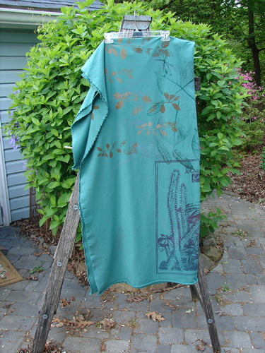 Barclay Heavy Weight Organic Sweatshirt Blanket Pony Garden Emerald OSFA, displayed on a wooden ladder, showcases a botanical motif with raw, curly edges, embodying Bluefishfinder.com's creative, vintage aesthetic.