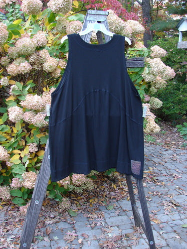 2000 Rayon Lycra Rib Crossroad Pullover Unpainted Black Size 2: A black shirt and vest on a wooden rack, showcasing the extreme A-line shape, V neckline with crisscross stitchery, and signature 2k patch.
