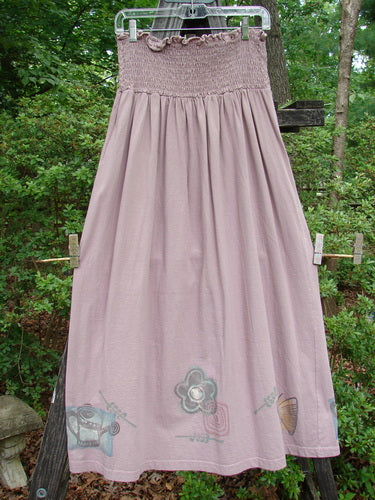 A 1995 Smocked Skirt Garden Patio Rose Size 2 displayed on a clothesline, showcasing detailed smocking, garden-themed paint, and a flowy, full silhouette, exemplifying vintage Blue Fish Clothing style.