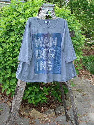 Barclay Three Quarter Sleeved A Lined Tee Wandering Dust Plum Size 0 displayed on a wooden stand, featuring a slate-gray hue with a blue-and-white WANDERING print, embodying vintage Blue Fish creativity.