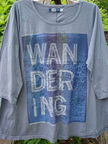 Barclay Three Quarter Sleeved A Lined Tee Wandering Dust Plum Size 0, features a blue graphic with “WAN / DER / ING” text. The shirt showcases a rounded neckline and curly edgings.