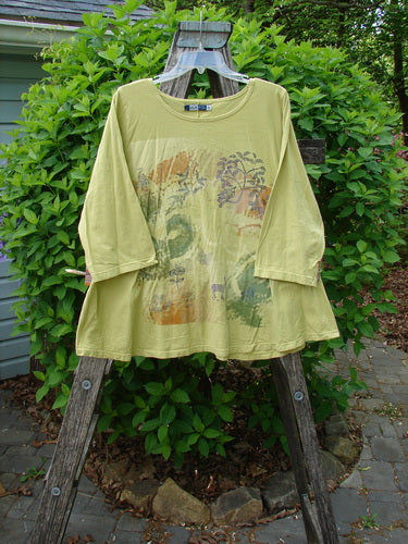 Barclay Three Quarter Sleeved A Lined Tee Field Friend Citron Size 0, featuring a rounded, rolled neckline and abstract nature print, displayed outdoor on a wooden trellis.
