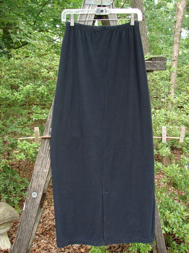 Alt text: 1995 Cotton Lycra Column Skirt Unpainted Black Tiny Size 2 displayed on a wooden ladder, showcasing its full elastic waistline, tapering shape, and pegged hemline.