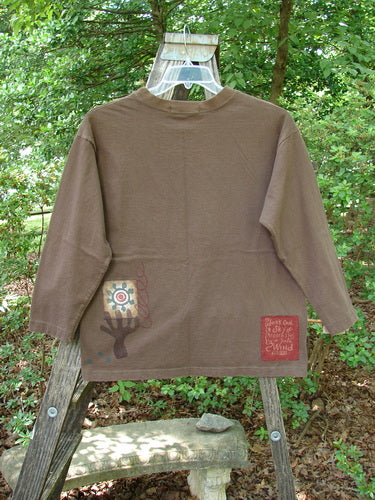 1996 Long Sleeved Tee Single Flower Molasses Size 0 displayed on a swinger, showcasing its thicker ribbed neckline, drop shoulders, and longer square shape, with a visible Blue Fish signature patch.