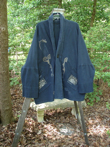 1995 Reprocessed Deco Jacket Star Rise Black OSFA displayed on a wooden stand, featuring drop dolman shoulders, long arms, and diagonal oversized painted pockets.