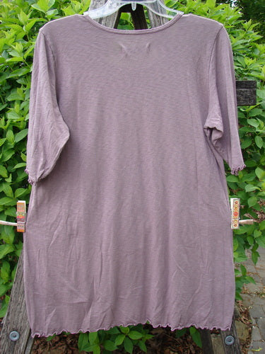 Barclay Slub Modal Three Quarter Sleeved Cafe Tee Merry Farm Mallow Size 0, displayed outdoors, features a loose fit, three-quarter sleeves, rounded neckline, and lettuce-ruffle edges against leafy shrubs.