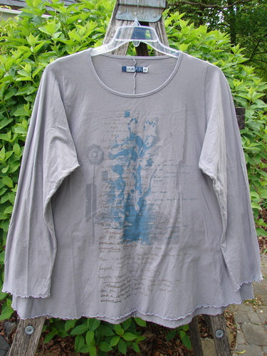 Barclay Long Sleeved Cafe Tee Poetry Garden Grey Day Size 0, features a loose A-line cut with scalloped edges and an abstract faded graphic, hanging outdoors on a ladder.