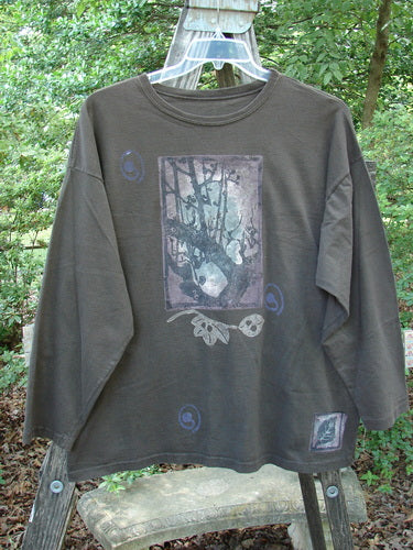Alt text: 1994 Long Sleeved Tee Forest Leaf Humus Size 1 displayed on a hanger, showcasing its graphic design with drop shoulders and a slightly thicker ribbed neckline.