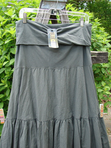 Barclay NWT Batiste Fold Over Silhouette Skirt Unpainted Chimera Size 1, displayed outdoors on a hanger against foliage, showcasing its tiered design, generous A-line flair, and soft waistline.