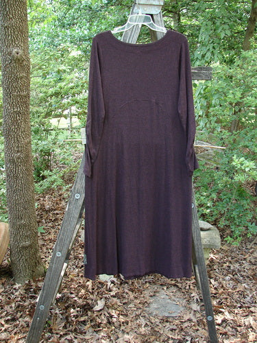 Alt text: 2000 Patched Rayon Lycra Rib Julia Dress Cassis Heather Size 0 displayed on a wooden ladder, showcasing its long, flowing style with a crisscross front and gathered forearms.