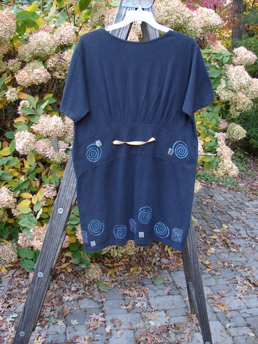 Image alt text: "1992 Little Storma dress with garden bug theme, featuring a black dress on a wooden rack"