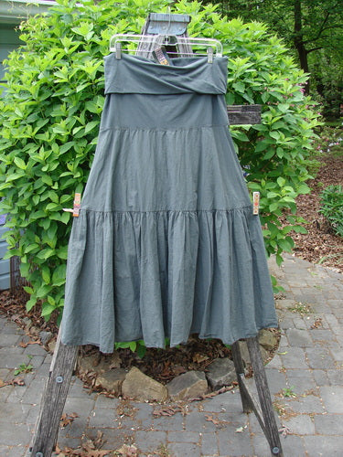 Barclay NWT Batiste Fold Over Silhouette Skirt Unpainted Chimera Size 1 hung on a wooden stand, showcasing its tiered design and soft flared silhouette, with a relaxed fit waistband and generous sweep.