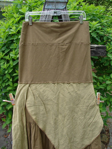 Barclay Fold Over Silk Accent Silhouette Skirt Unpainted Bone Size 0 displayed outdoors, featuring a two-tone olive design with a smooth upper knit and asymmetrical draped lower layers against leafy shrubs.