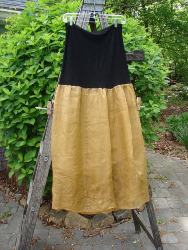 2000 Silk Organza Aios Dana Skirt Celtic Wind Bone Size 0 hanging on a wooden ladder, showcasing its black lycra waistband and golden flared silk organza skirt, embodying timeless elegance.