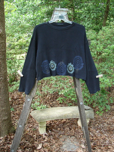 1996 Thermal Boxy Top Gear Black OSFA displayed on a wooden ladder, showcasing its wider boxier shape, drop shoulders, longer arm lengths, ribbed neckline, and colorful abstract gear art.