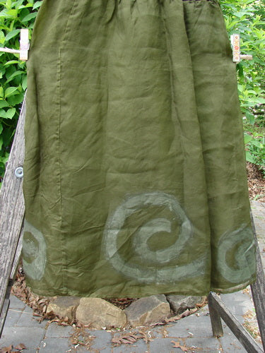 2000 Silk Organza Aios Dana Skirt Celtic Lichen Size 1, elegantly drying outdoors, showcases a spiral motif along the hem, gathered waistband, and decorative clothespins against a natural garden backdrop.