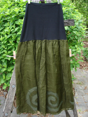 2000 Silk Organza Aios Dana Skirt Celtic Lichen Size 1, featuring a black upper and olive-green lower with spiral motifs, hangs on a wooden frame, embodying BlueFishFinder's vintage, creative aesthetic.