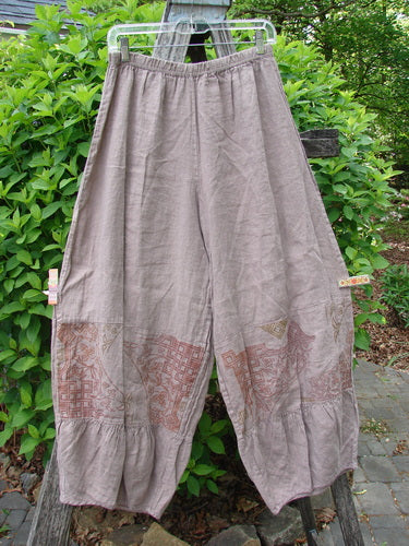 Barclay Linen Meadow Pant Celtic Vine Stone Oriel Size 0: Loose-fitting, wide-leg trousers with elastic waist, patchwork-style pattern in rust and beige, and flared ruffle hem, perfect for spring or summer.