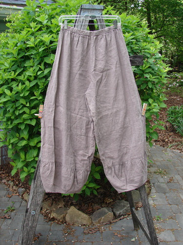 Barclay Linen Meadow Pant Celtic Vine Stone Oriel Size 0, featuring wide-leg, flowy design with elastic waist and gathered panels, displayed on a hanger outdoors against a garden backdrop.