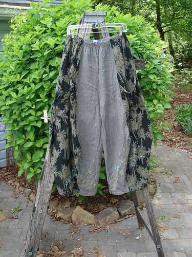 Barclay Linen Pucker Accent 4 Square Pant Tropical Black Grey Size 0: Loose-fitting harem pants with a gray central panel, black foliage-patterned side panels, draped on an outdoor ladder, showcasing unique drape and movement.
