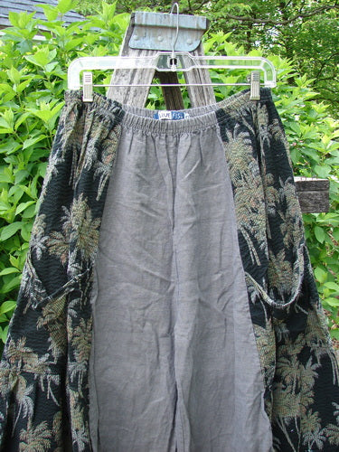 Barclay Linen Pucker Accent 4 Square Pant Tropical Black Grey Size 0 hangs outdoors, showcasing a light gray inner layer with a dark tapestry-style outer layer featuring palm motifs and large curved pockets.