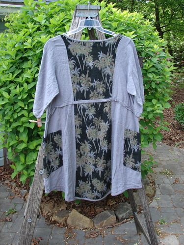 Barclay Linen Pucker Heart and Soul Dress Tropical Black Grey Size 0, featuring a knee-length design with palm-leaf motifs, inset side pockets, and a deep V-neckline, displayed on a garden ladder.