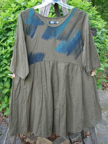 Barclay Linen Two Pocket Dolly Dress Brush Paint Wood Size 0 features a loose-fitting, olive-green tunic with a round neckline, elbow-length sleeves, flared skirt, and striking dark and teal brush-stroke accents.