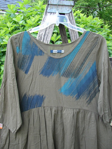 Barclay Linen Two Pocket Dolly Dress Brush Paint Wood Size 0 displayed on a rustic ladder, featuring a flouncy skirt, dropped empire waist, wide hem, and artistic brush-stroke bodice with dual drop pockets.