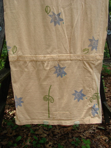 Alt text: 1990 B Base Dress Double Fish Marigold Altered OSFA displayed on a white towel with blue flowers, showcasing its unique design, including a rounded hem and ruching accents.