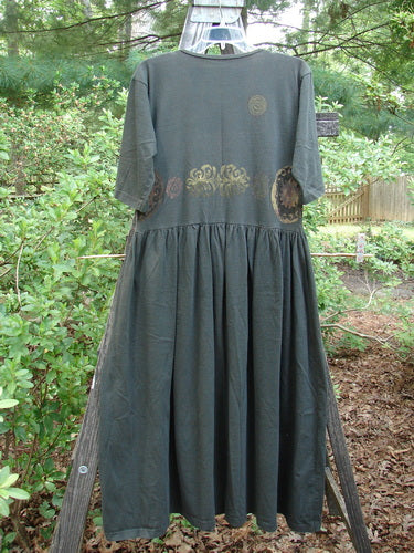 A 1992 Short Sleeved Simple Dress in Metallic Black Sand, displayed on a swing, showcasing its semi-dropped waistline and full draping lower.