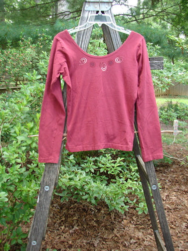 A 1995 Cotton Lycra Ballina Long Sleeved Layering Top Necklace Hollyberry Size 2 displayed on a wooden ladder, highlighting its ballerina neckline and fitted, shapely design.