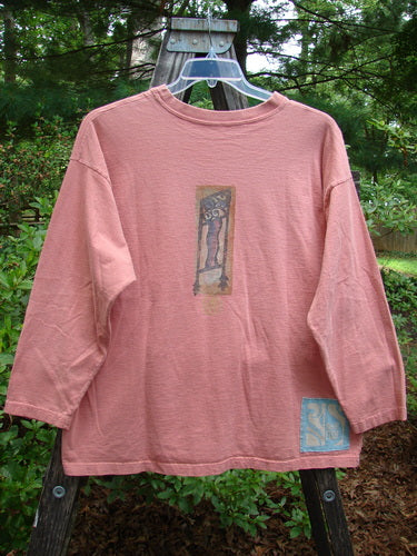 Alt text: 1995 Long Sleeved Tee Vintage Column Papaya Size 1, displayed on a swinger, featuring a thicker ribbed neckline, drop shoulders, and superior vintage paint details.