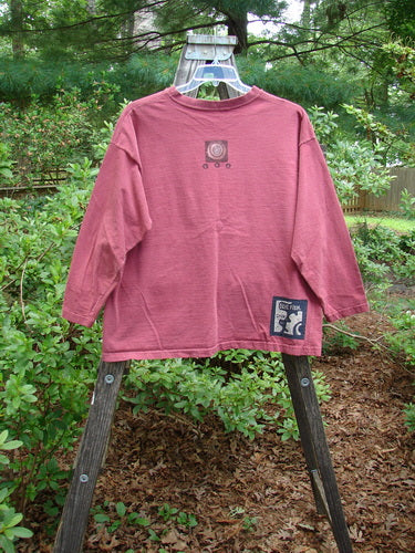 1995 Long Sleeved Tee Vintage Train Hollyberry Size 1 displayed on a hanger outdoors, showcasing its drop shoulders, thicker ribbed neckline, and hem paint accent in a serene natural setting.