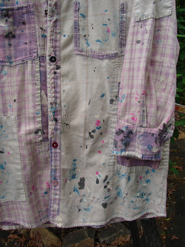 Magnolia Pearl Flannel Patched Surfside Shirt Sun Bleached OSFA hanging outdoors, showcasing hand-distressing, significant paint splatters, button-front design, long sleeves, and unique patchwork, reflecting creative individuality.