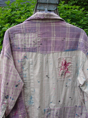 Magnolia Pearl Flannel Patched Surfside Shirt features a purple plaid top and lighter lower half, adorned with paint splatters and cherub patch, reflecting Bluefishfinder.com's vintage, creative style.