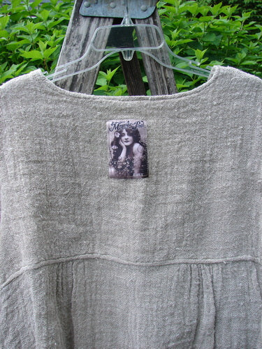 Magnolia Pearl Fisherman's Weave Asymmetrical Ruffle Jacket OSFA displayed on a hanger over a wooden ladder, featuring a textured linen weave, ruffled hem, and vintage-style portrait pinned on the front.