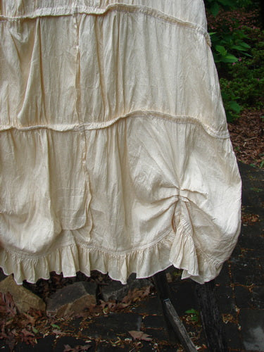 Magnolia Pearl Silk Cotton Drapery Dress Butter Creme OSFA features tiered gathers, pintucks, and ruffled hem, draped outdoors, showcasing its elegant silhouette and airy, vintage-inspired design.